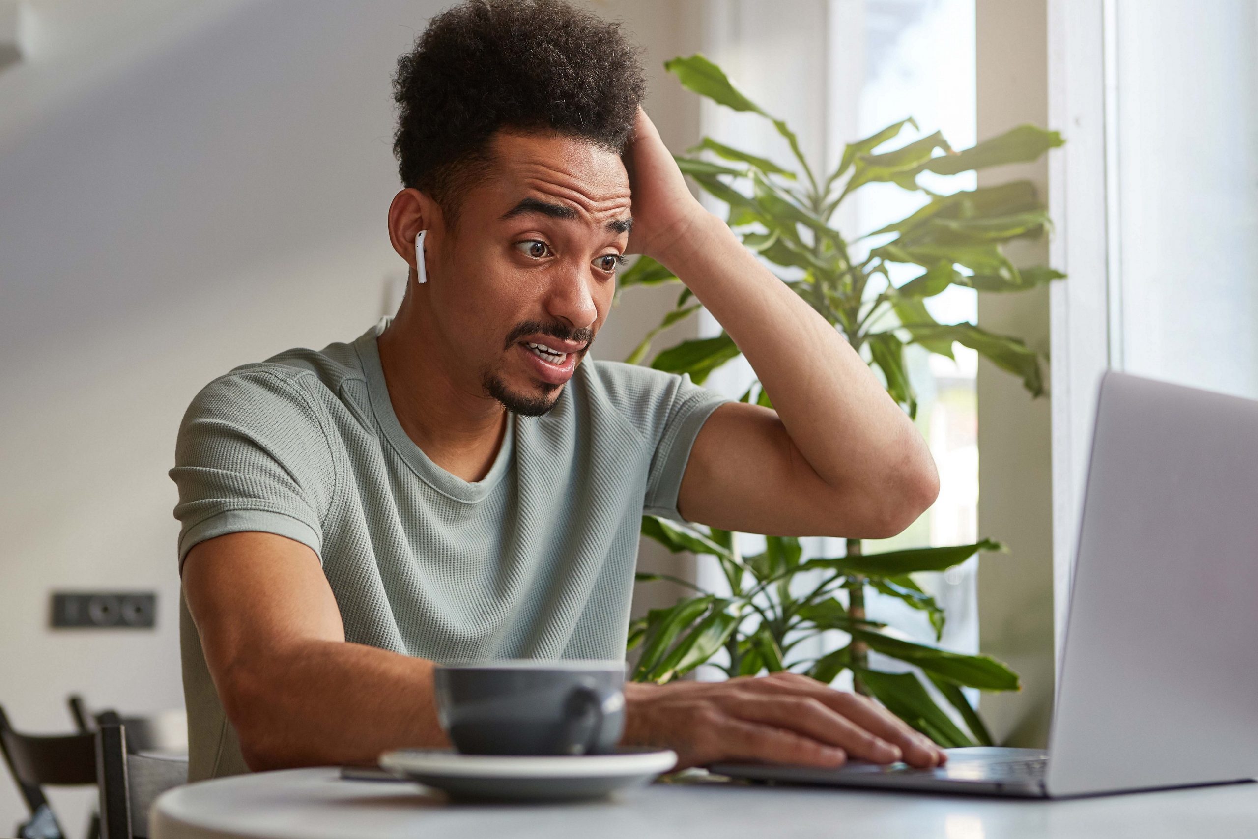 Мужчина с ноутбуком на кухне. Афроамериканец работает за ноутбуком. A boy Dark holding an Laptop.